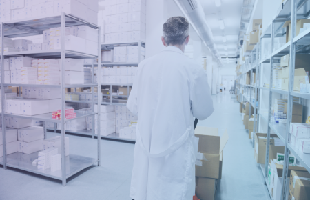Pharmacist walking alongside shelves of medication