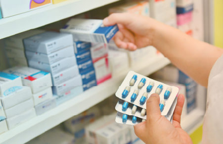 Pharmacist stocking meds on shelf